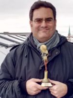 Frédéric Eiguer montrant le trophée qui lui a été décerné par le SOUTH FILM ARTS ACADEMY FESTIVAL (SFAAF), janvier 2019 Frédéric Eiguer